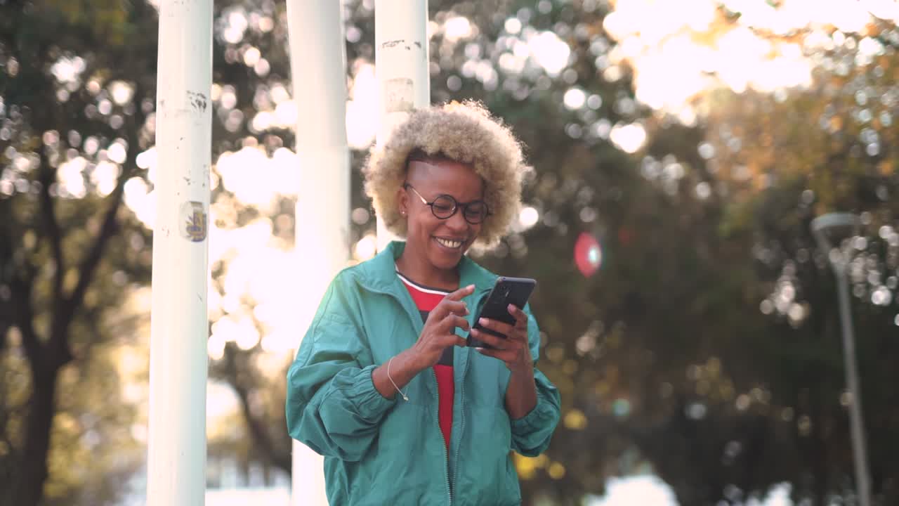 mujer joven alegre usando un teléfono inteligente al aire libre