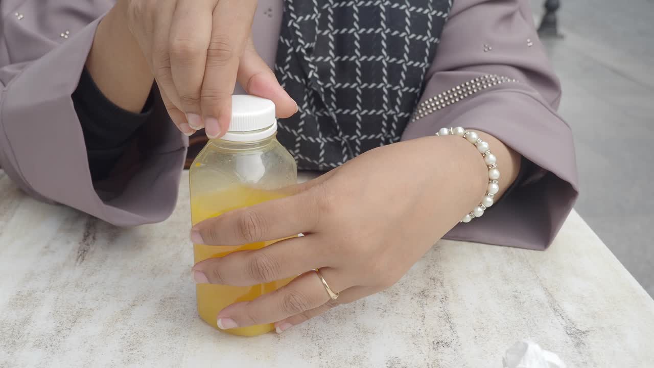 mujer abriendo una botella de jugo de naranja