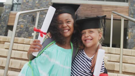 video de niñas diversas felices con sombreros de graduación y con diplomas en la mano