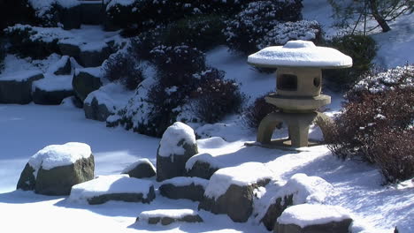 linterna japonesa cubierta de nieve junto a un estanque