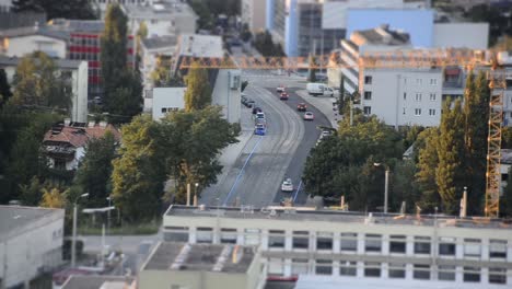 timelapse con efecto miniatura de una calle en una ciudad pequeña con autos conduciendo y deteniéndose en una sección transversal con casas y una grúa alrededor