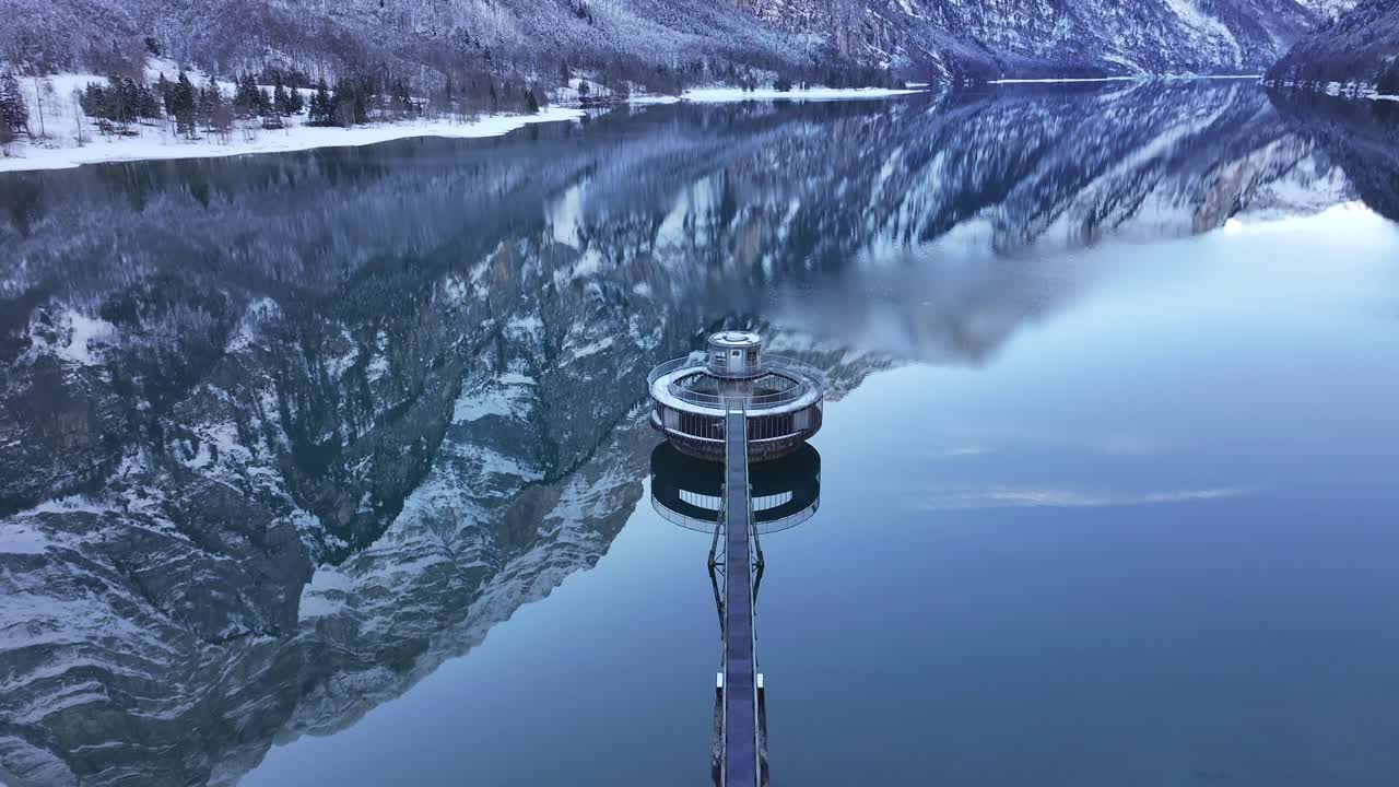 A breathtaking view of the Klöntalersee in Klöntal, Switzerland. The serene lake reflects the snow-capped mountains that rise dramatically on either side, creating a mesmerizing mirror image.