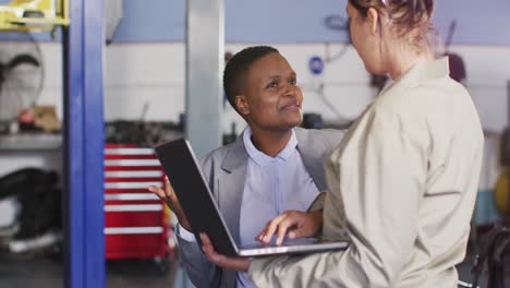 video of two diverse car mechanic and business owner with laptop searching for car parts