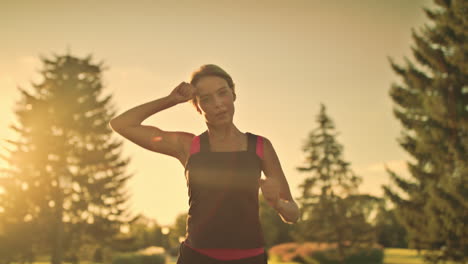 Sportliche-Frau-Beim-Training-Und-Wischt-Sich-Abends-Im-Sommerpark-Den-Schweiß-Von-Der-Stirn