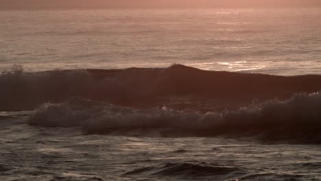 ocean waves rolling on the beach at sunset