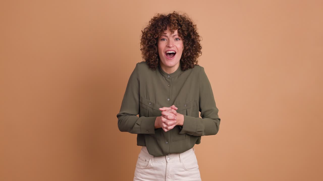 Stunned young woman standing with opened mouth on beige background