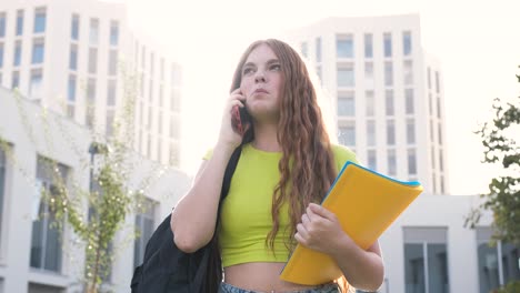 Smiling female student chatting on cellphone on university campus