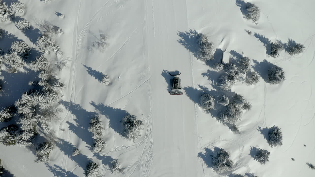 Aerial view of a snow groomer on a snow-covered ski slope