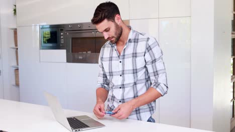 hombre guapo usando computadora portátil y tarjeta de crédito