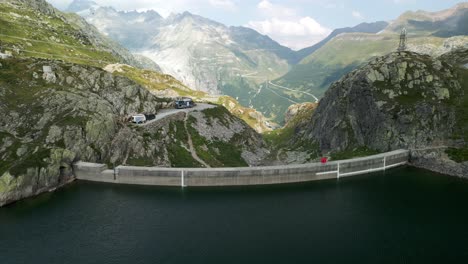 scenic aerial view of totensee lake and dam of grimsel pass in summer season with mountain range in background, switzerland