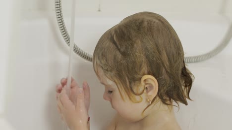 attractive three years old girl takes a bath. cleaning and washing hair