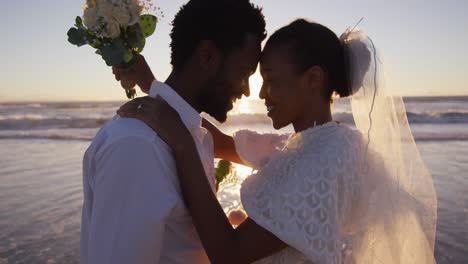 Una-Pareja-Afroamericana-Enamorada-De-Casarse,-Mirándose-En-La-Playa-Al-Atardecer