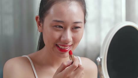 mujer aplicando lápiz labial rojo