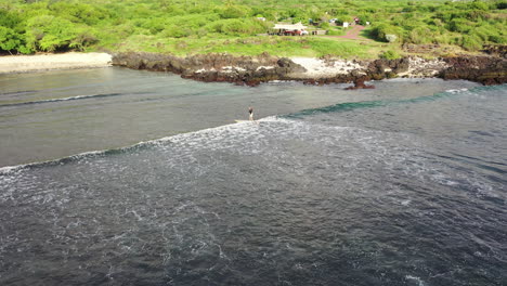 A-paddleboarder-surfs-a-wave-on-a-on-sup-board-in-the-ocean-in-the-waters-of-Reunion-Island