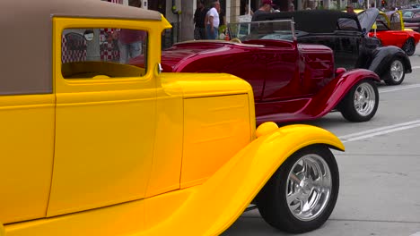 People-wander-on-the-streets-of-a-small-town-looking-at-classic-cars-on-display-1