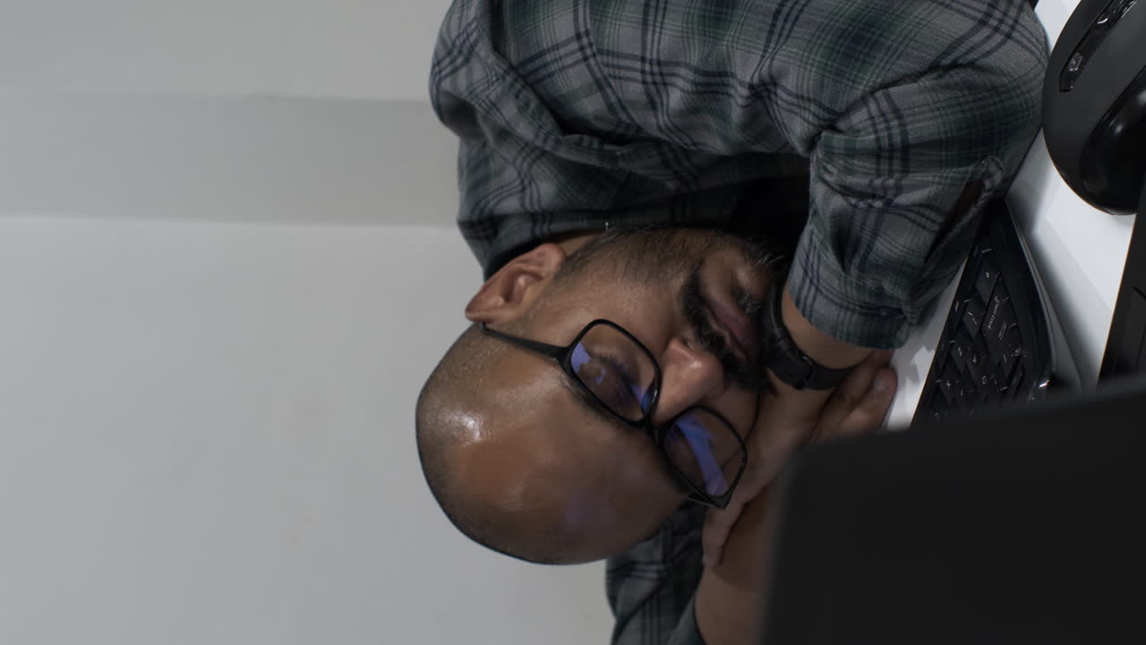 Ethnic Minority Male Wearing Glasses Sleeping At Desk In Office