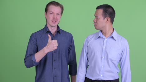 two businessman having different opinions against green studio background