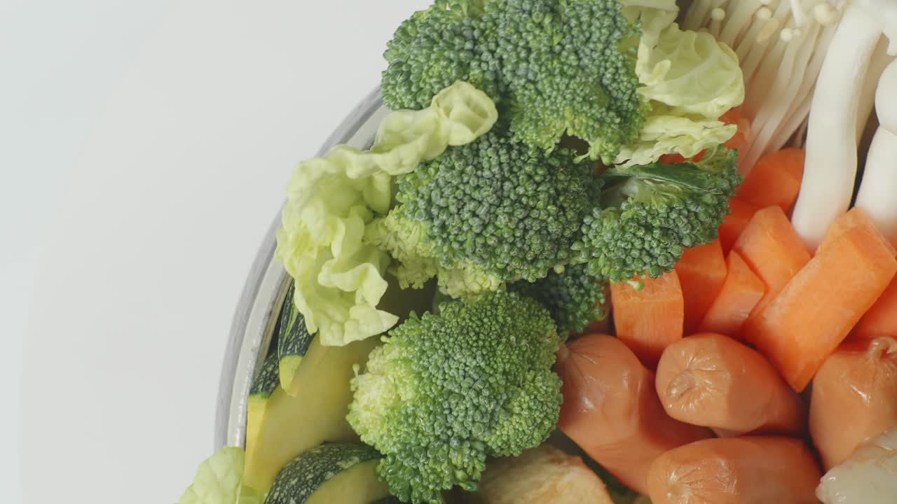 Primo piano di una pentola di ingredienti per Shabu che gira su un tavolo bianco in cucina