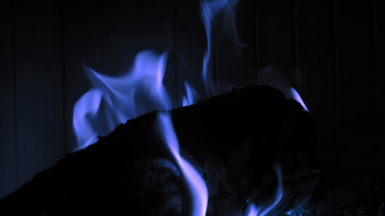 나무 통나무에 있는 벽난로에서 불타는 푸른 불꽃