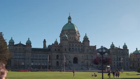 wide shot of the legislative assembly of british columbia in victoria, bc on a gorgeous sunny day with blue skies and people walking around on green grass