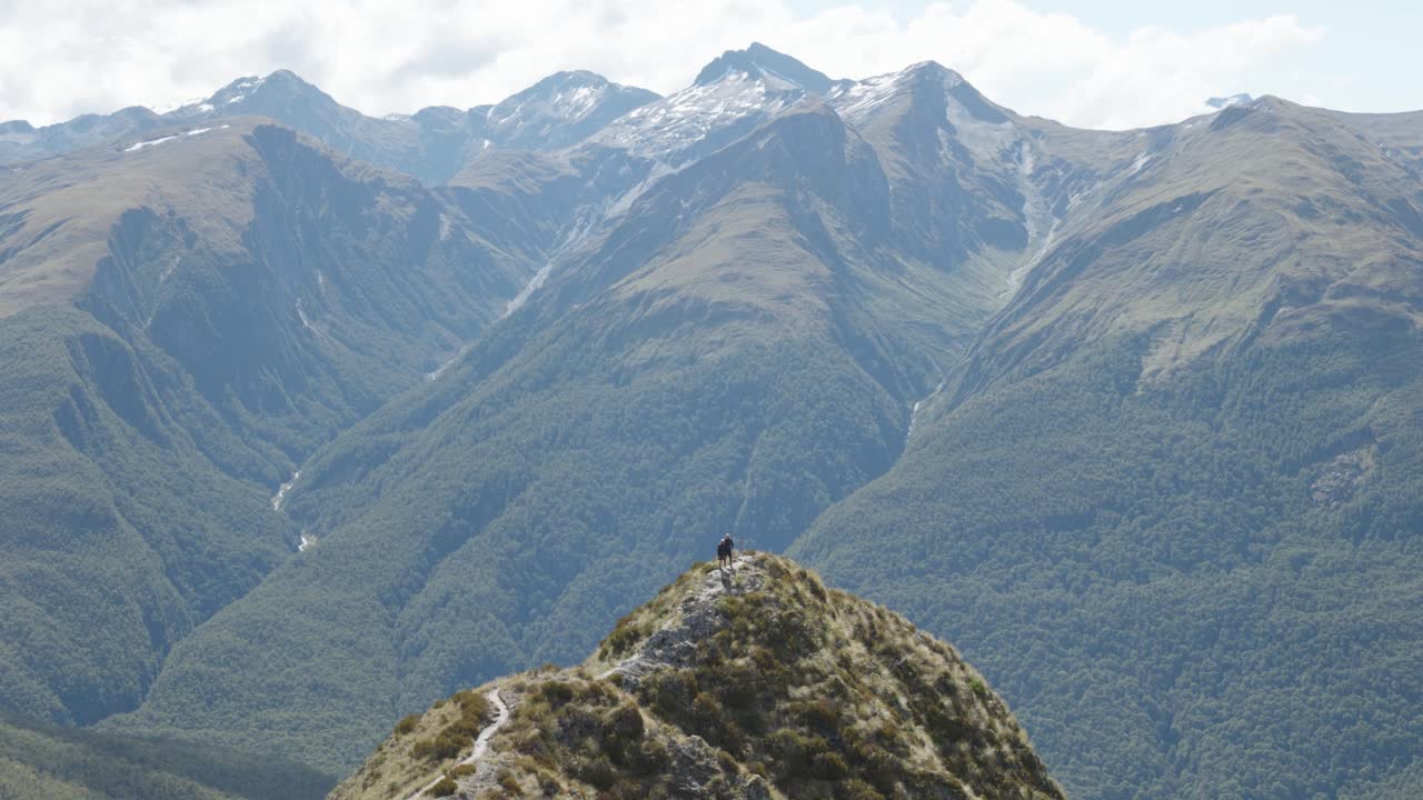 personas caminando a través de una cordillera con montañas detrás de ellos en la pista de brewster en el parque nacional mount aspiring, nueva zelanda