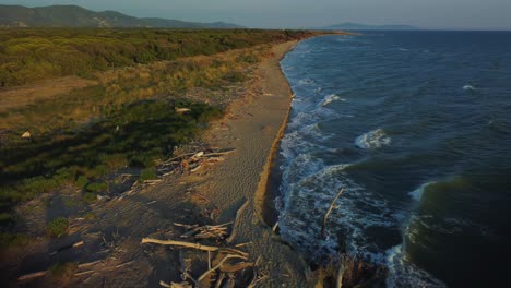 Imágenes-Cinematográficas-De-Drones-Aéreos-Que-Vuelan-Hacia-Adelante-Sobre-Una-Playa-De-Arena-Al-Amanecer-En-La-Costa-Cerca-De-Alberese-En-El-Icónico-Parque-Natural-Maremma-En-Toscana,-Italia,-Con-Olas,-Islas-Y-Un-Espectacular-Cielo-Rojo