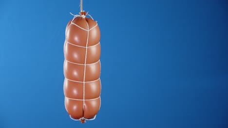 a whole stick of boiled sausage hanging from a rope.