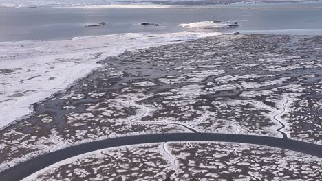 aerial drone zoom in to borgarfjörður, iceland’s snow-covered landscape, icy coastline, islands and mountain.