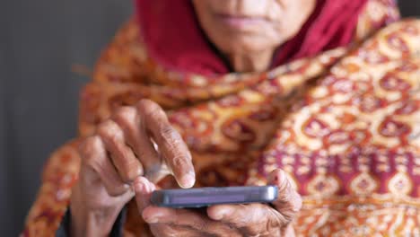 Mano-De-Mujer-Mayor-Usando-Teléfono-Inteligente-De-Cerca