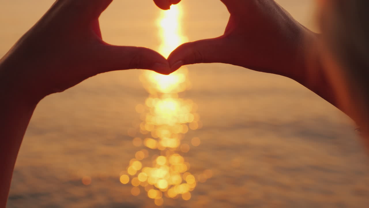 las manos femeninas muestran la forma del corazón sobre el mar donde sale el sol hermosa escena romántica