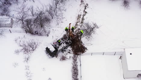 Luftaufnahme-über-Ingenieurarbeitern,-Die-Beschädigte-Strommasten-Auf-Schneebedeckten-Ländlichen-Ackerflächen-Ersetzen