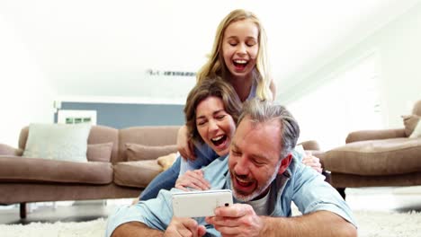 Happy-family-in-lying-on-rug-and-talking-a-selfie-on-mobile-phone