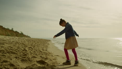 niña jugando sola en la playa al atardecer. niño lindo divirtiéndose en vacaciones familiares.