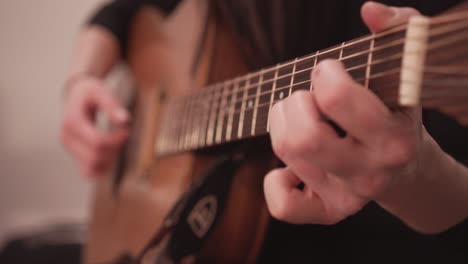 acoustic guitar fretboard and hand playing chords, close up view with no face