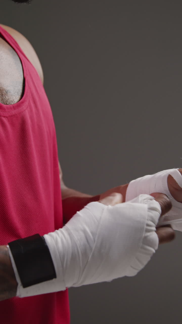 video vertical de primer plano de un boxeador masculino envolviendo las manos con vendajes protectores antes de un partido de boxeo o sesión de entrenamiento 2