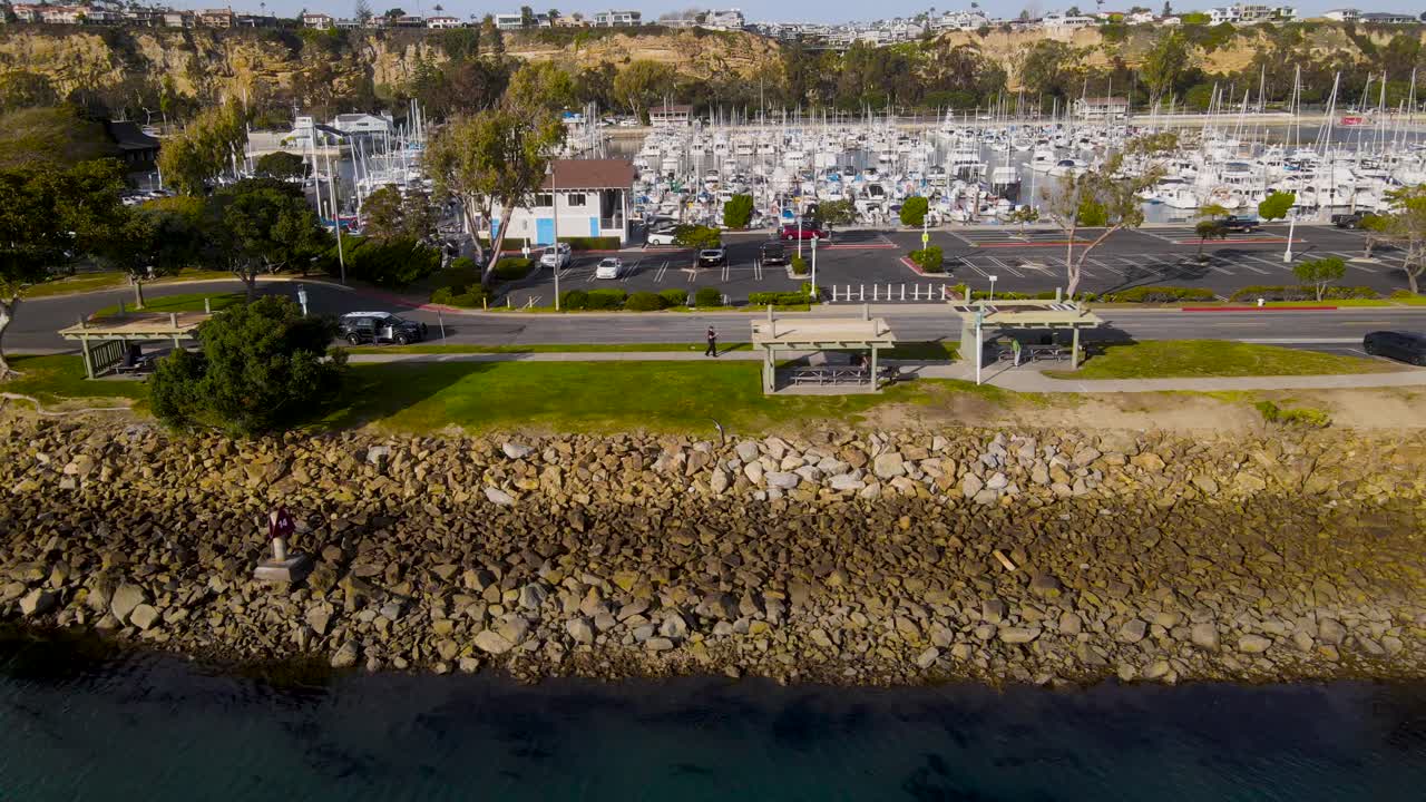 보트가 있는 항구의 해변을 마주하고 있는 녹색 통로를 따라 있는 공중 팬