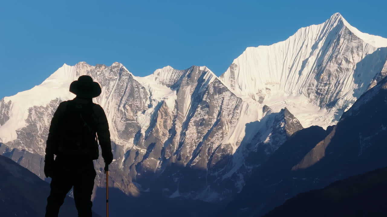 A medium drone shot capture a male tourist entering the majestic landscape of snow capped Himalayas in Langtang National Park Nepal. He enjoys the mesmerizing view while hiking and trekking in trails.
