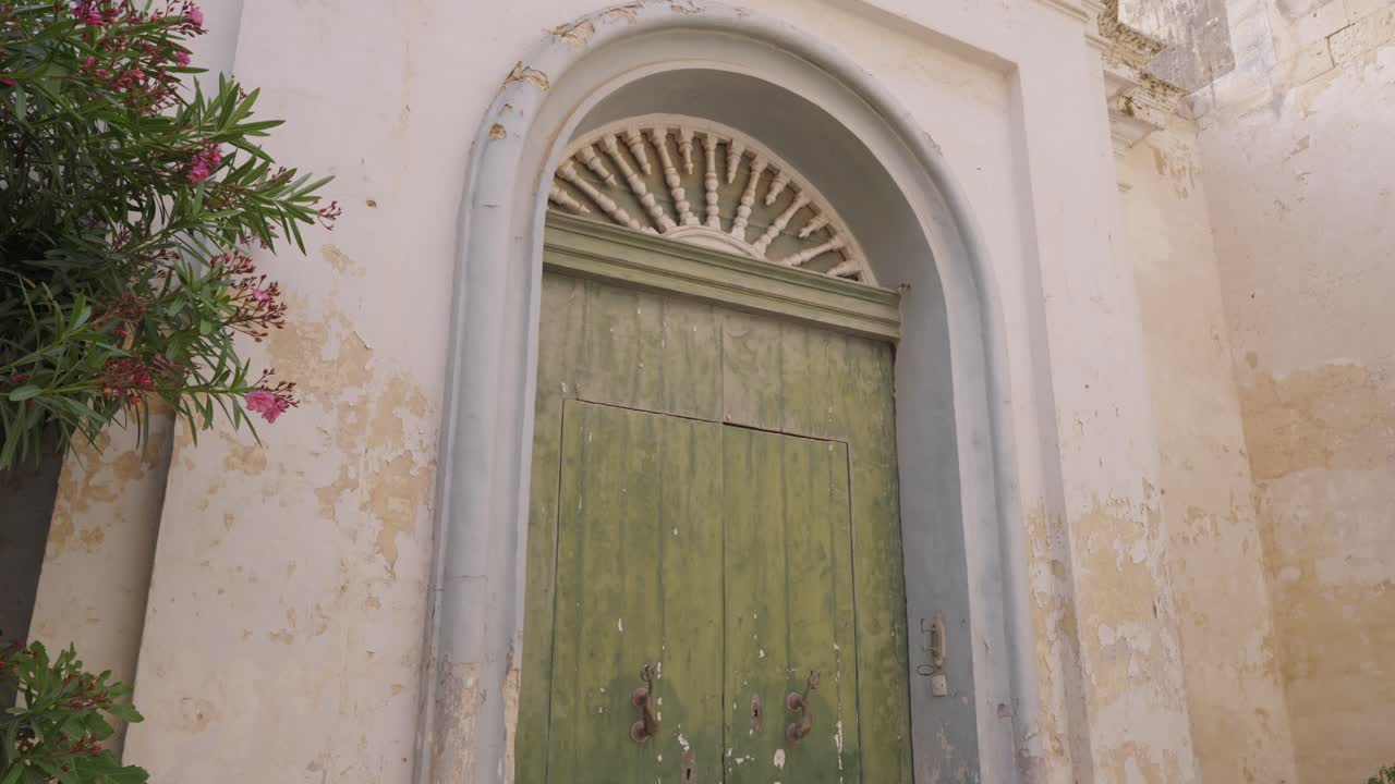 Rustic old wooden door with faded green paint in Mediterranean Malta