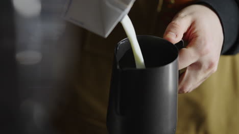 barista pouring milk into pitcher