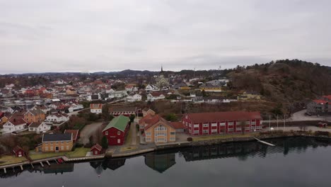 kjellnabben and bivika in grimstad with city center and church in background - aerial from seaside with reflections in water surface - norway