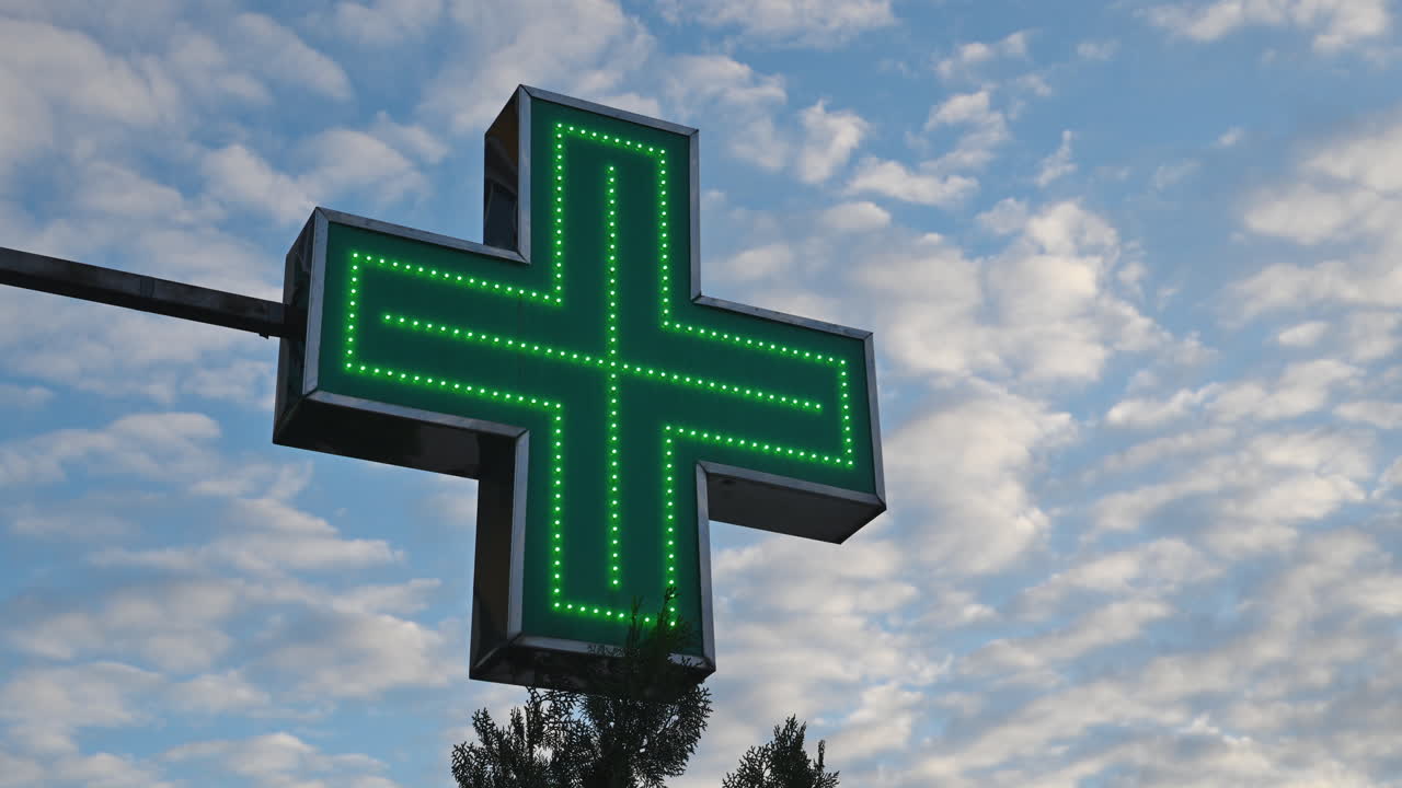 cruz de farmacia verde iluminada frente a la farmacia