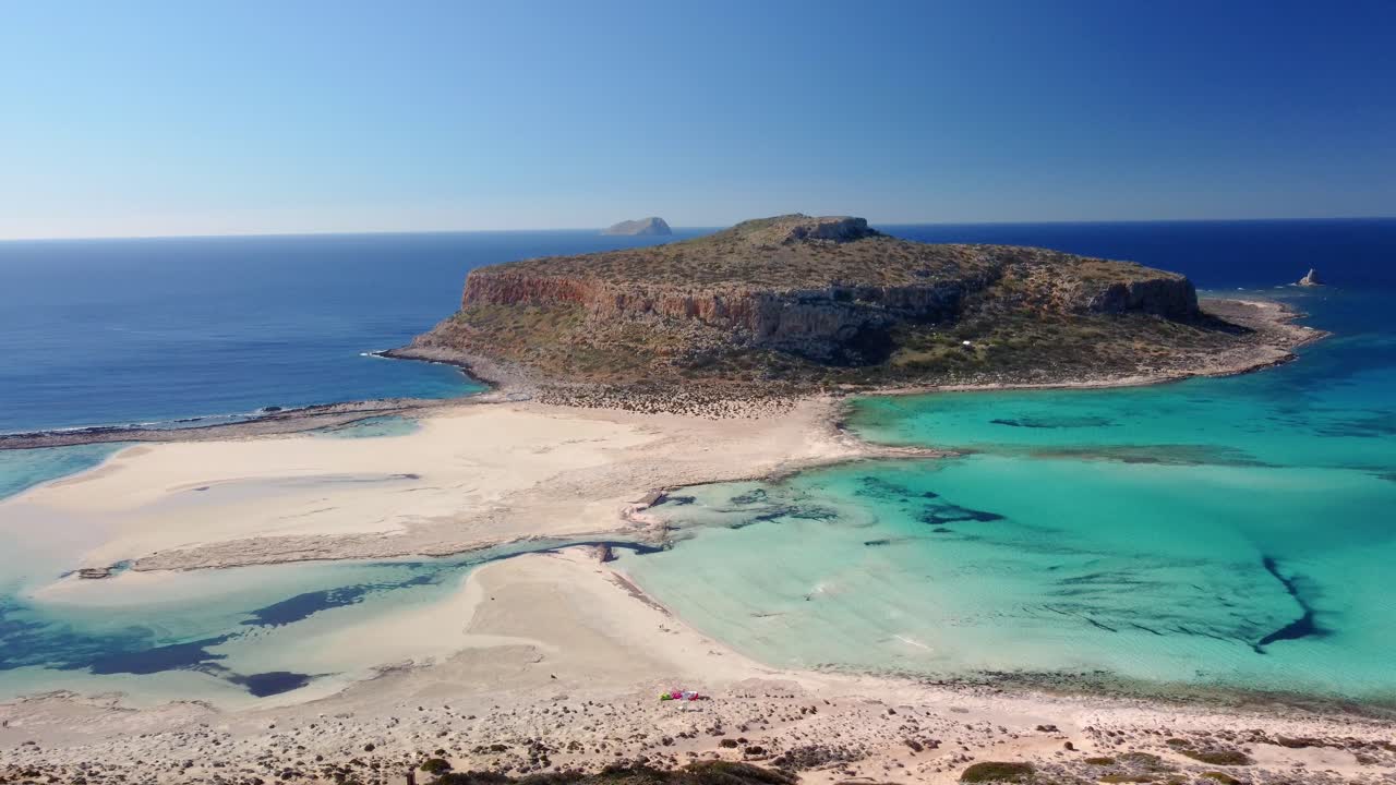 Woman standing on top of cliff and observing beautiful white sand beach with turquoise water. Sunny summer day. Paradise. Crete, Greece
