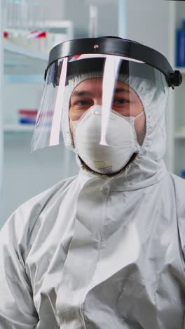 vertical video: doctor in protection suit looking exhausted at camera