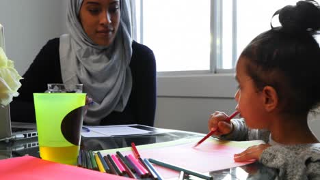 Young-mother-helping-her-daughter-with-homework-on-table-at-home-4k