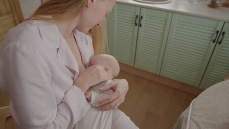 mother breastfeeding baby in kitchen