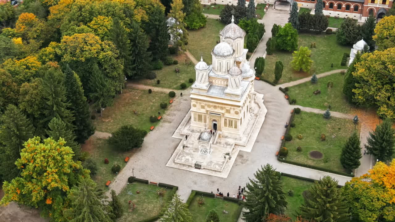 Aerial drone view of The Cathedral of Curtea de Arges, Romania. Square with greenery and people