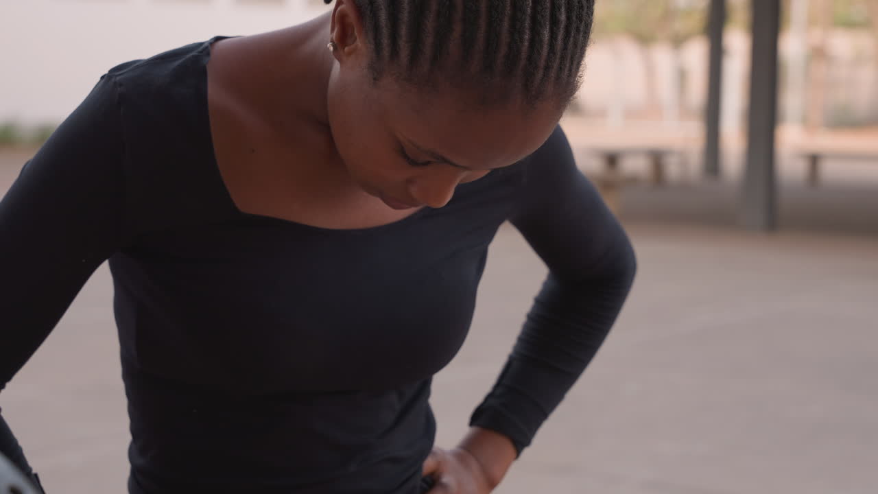 Silent dance preparation. Graceful woman adjusts costume patiently. Focused dancer with neat cornrows gets ready quietly. Poised woman adjusts her dance outfit with calm focus and graceful movements