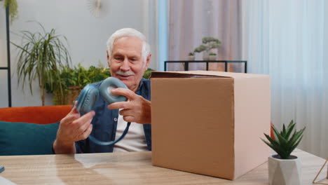 hombre mayor feliz comprador desempaquetando auriculares caja de cartón entrega de paquetes compras en línea compra