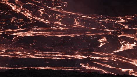 dark wrinkle surface on slow flowing lava river at night, active volcanic field