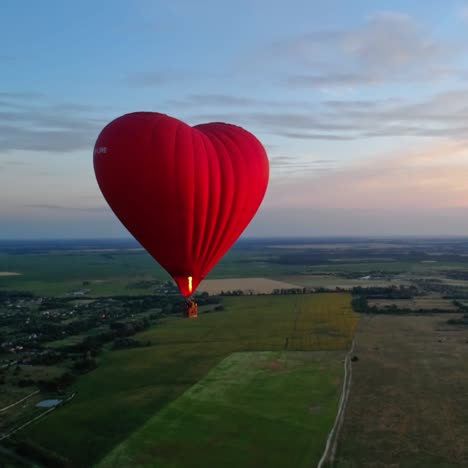 red airship in the shape of a heart. hot air balloon in the sky over a field in the countryside flying in the beautiful evening sky.